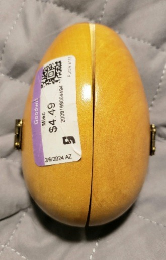 A wood egg with amber yellow varnish and a Goodwill price sticker. 